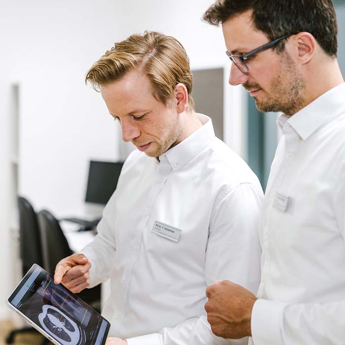 PD Dr. med. T. Hickethier und Dr. med. N. Krasny betrachten radiologische Aufnahmen auf einem Tablet-Computer.