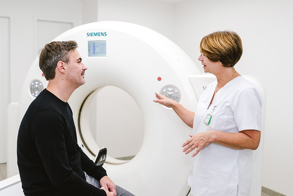 Mitarbeiterin der Radiologie Heinrichsallee spricht mit Patient vor MRT-Gerät