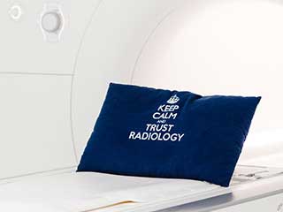 MRT-Gerät mit blauem Kissen mit Aufschrift "Keep Calm and Trust Radiology"