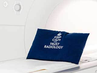 MRT-Gerät mit blauem Kissen mit Aufschrift "Keep Calm and Trust Radiology"